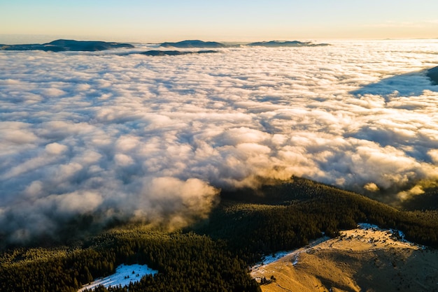 Vista aérea do nascer do sol vibrante sobre colinas de montanha cobertas com floresta de abetos perenes no outono.