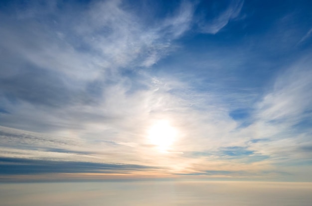 Vista aérea do pôr do sol amarelo brilhante sobre nuvens densas brancas com céu azul em cima