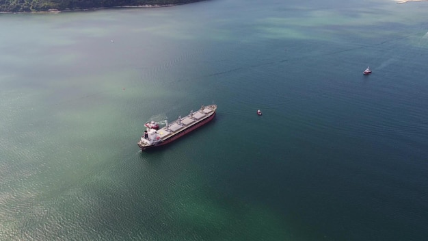 Vista aérea do rebocador auxiliando grande navio de carga graneleiro Grande navio escoltado por rebocador