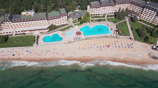 Vista aérea do resort de Golden Sands, na Bulgária, durante a temporada de verão. Uma série de hotéis, piscinas e multidões de pessoas desfrutando do mar.