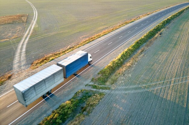 Vista aérea do semi-caminhão turva em movimento rápido com reboque de carga dirigindo na rodovia transportando mercadorias à noite. Transporte de entrega e conceito de logística.