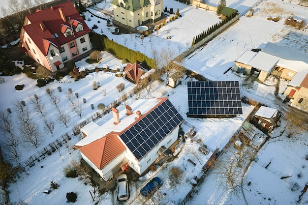 Vista aérea do telhado da casa com painéis solares cobertos de neve derretendo no final do inverno para produzir energia limpa Conceito de baixa eficácia de eletricidade renovável na região norte