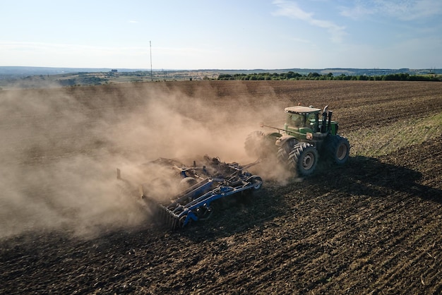 Vista aérea do trator arando o campo agrícola preparando o solo para a semeadura no verão