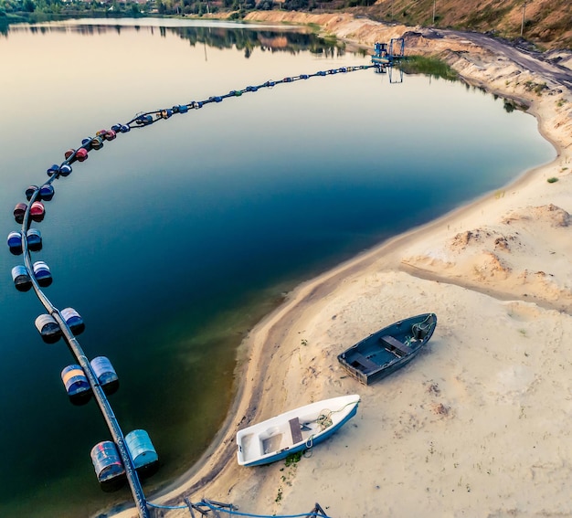 Vista aérea do tubo azul com barris no lago e dois barcos na praia de areia