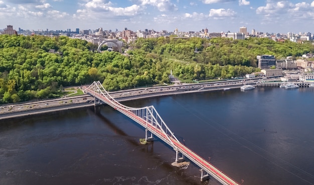 Vista aérea do zangão da ponte pedonal do parque, do rio dnieper e da paisagem urbana de kiev de cima, cidade de kiev, ucrânia