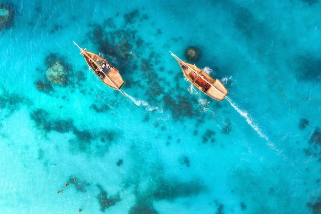 Vista aérea dos barcos de pesca na água azul clara ao pôr do sol no verão