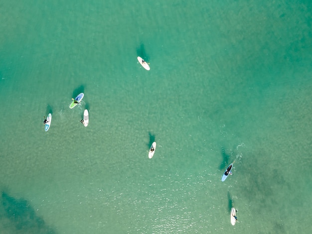 Vista aérea por dron de personas practicando Stand Up Paddle o SUP en el mar turquesa del Mediterráneo.