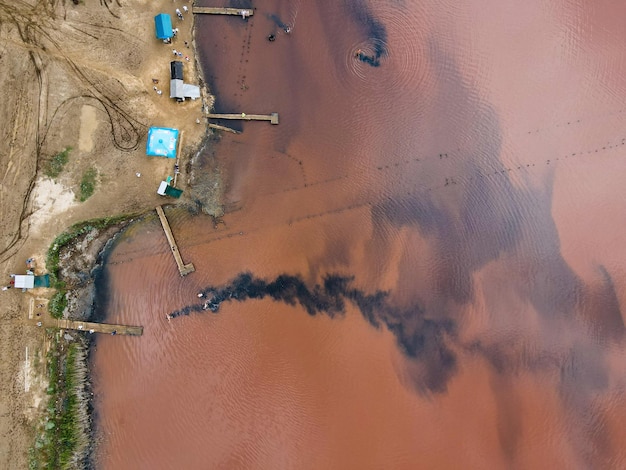 Vista aérea desde un dron sobre personas que se bañan en agua sucia color oxidado al aire libre