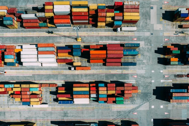 Vista aérea de drones de arriba hacia abajo de contenedores repartidos en un concurrido concepto de comercio internacional y logística portuaria