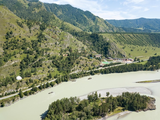 Vista aérea de drones en un centro de recreación turística en las montañas de Altai con edificios de hoteles y piscinas cerca del río verde en un cálido día de verano Viajes y turismo