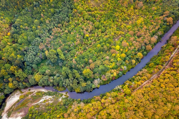 Vista aérea desde drones del río a través de colinas montañosas con árboles de otoño