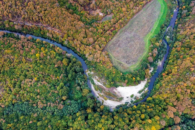 Vista aérea desde drones del río a través de colinas montañosas con árboles de otoño