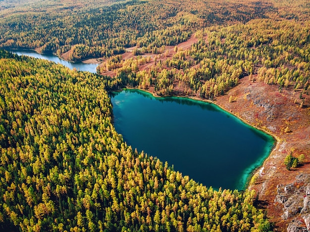 Vista aérea de un enorme lago con agua turquesa brillante que se encuentra justo en medio de un denso bosque saturado