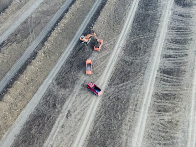 Vista aérea. Escavadeira carrega solo em caminhões