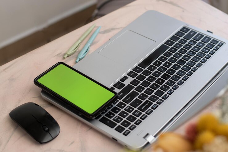 Foto vista aérea del escritorio de la casa con una computadora portátil y un teléfono celular con tecla de croma sobre el teclado