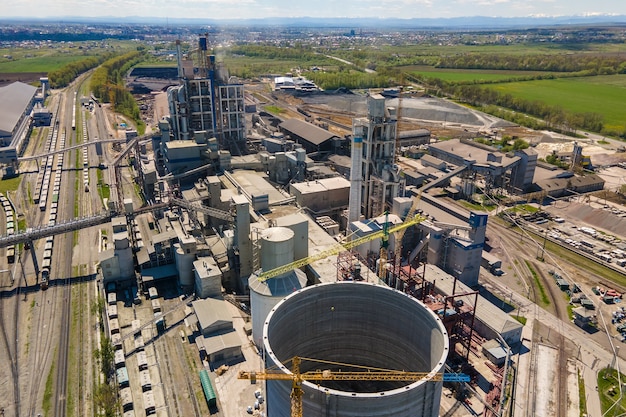 Vista aérea de la fábrica de cemento con alta estructura de hormigón y grúa torre en el área de producción industrial. Concepto de industria global y fabricación.