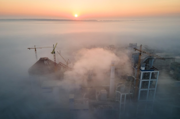 Vista aérea de la fábrica de cemento con estructura de planta de hormigón alto y grúa torre en el sitio de producción industrial en la mañana nublada Fabricación y concepto de industria global