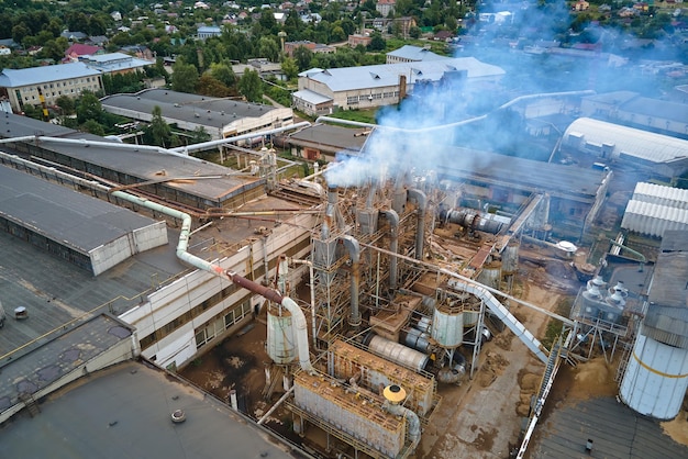 Vista aérea de la fábrica de procesamiento de madera con humo del proceso de producción que contamina la atmósfera en el patio de fabricación de la planta