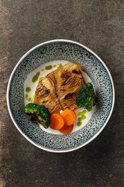 Vista aérea de filete de pescado a la parrilla servido con verduras