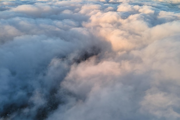 Vista aérea desde gran altura de una ciudad lejana cubierta de cúmulos hinchados que se forman antes de la tormenta en la noche Punto de vista del avión del paisaje nublado