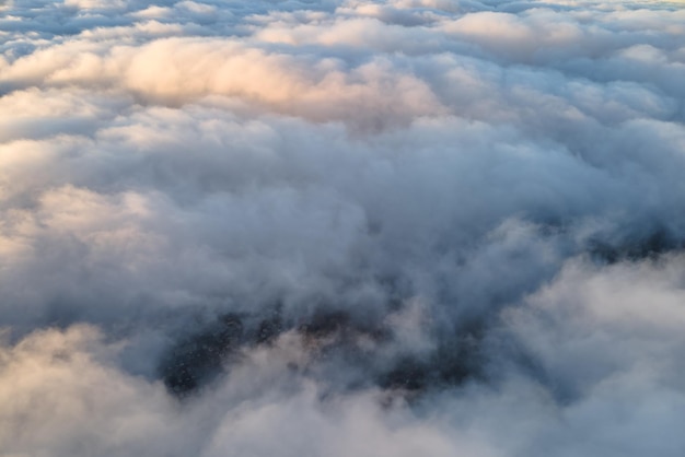 Vista aérea desde gran altura de una ciudad lejana cubierta de cúmulos hinchados volando antes de la tormenta Punto de vista del avión del paisaje en tiempo nublado