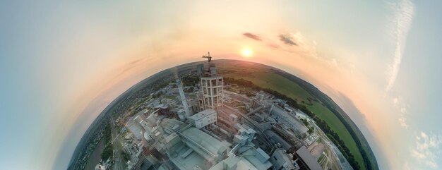 Vista aérea desde gran altura del pequeño planeta tierra con torre de fábrica de cemento con estructura de planta de hormigón alta en el área de producción industrial al atardecer Fabricación y concepto de industria global