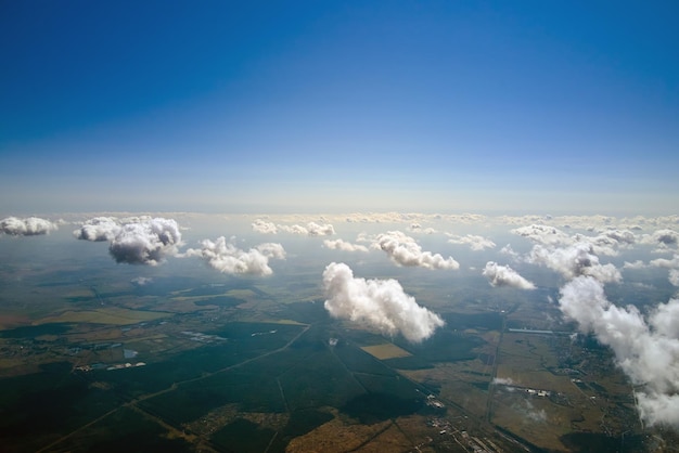 Vista aérea desde gran altura de la tierra cubierta de nubes cumulus hinchadas blancas en un día soleado.