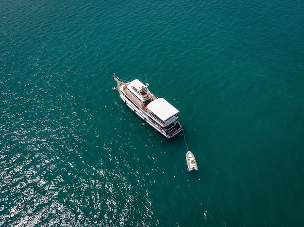 Vista aérea de la gran embarcación a motor con bote salvavidas, costados blancos y cubierta de madera; concepto de barcos.