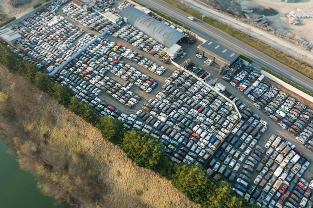 Vista aérea del gran estacionamiento del depósito de chatarra con filas de autos rotos desechados Reciclaje de vehículos viejos