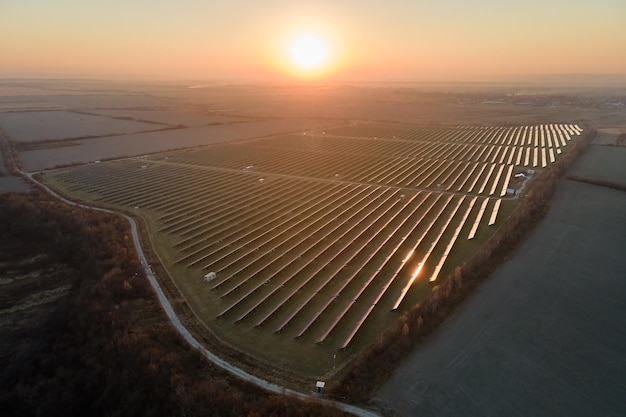 Vista aérea de una gran planta de energía eléctrica sostenible con muchas filas de paneles solares fotovoltaicos para producir energía eléctrica limpia al atardecer Electricidad renovable con concepto de cero emisiones