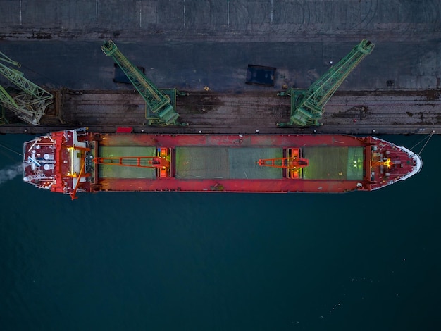 La vista aérea del granelero del buque de carga se carga en el puerto al atardecer