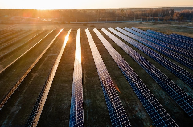 Vista aérea de una granja de paneles solares de tamaño industrial durante la puesta del sol que ilustra la mezcla de tecnología y naturaleza