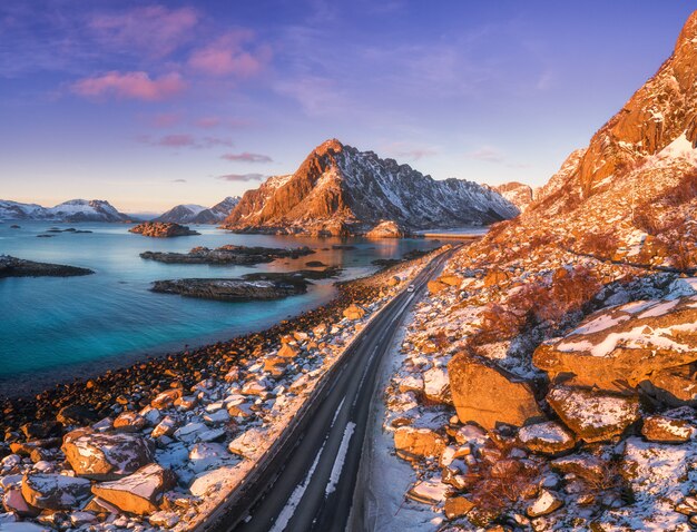 Vista aérea de la hermosa carretera de montaña cerca del mar, montañas, cielo púrpura al atardecer