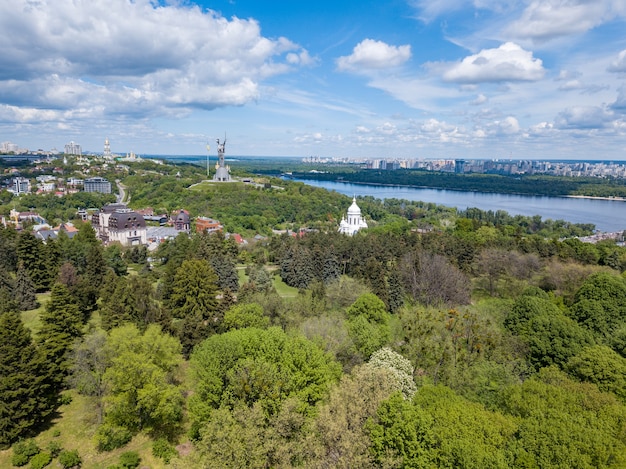 Vista aérea de la hermosa naturaleza verde en el jardín botánico, estatua, iglesias, río, edificios de la ciudad y cielo nublado en verano