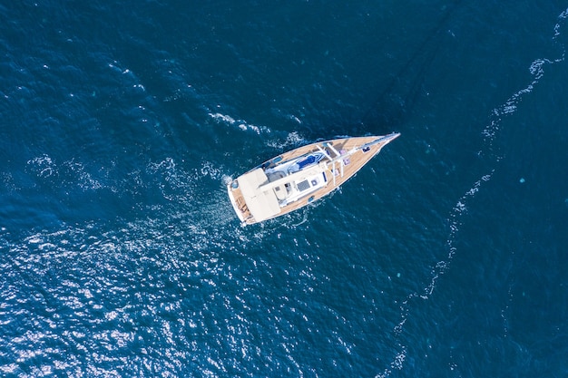 Vista aérea de un hermoso yate de vela blanco con una vela de color.