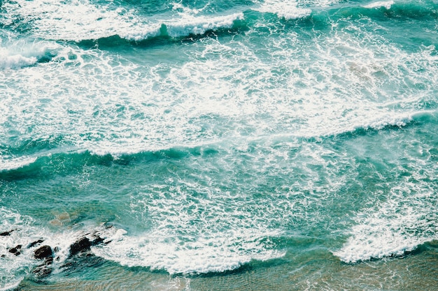 Vista aérea horizontal de las olas en una playa de aguas cristalinas