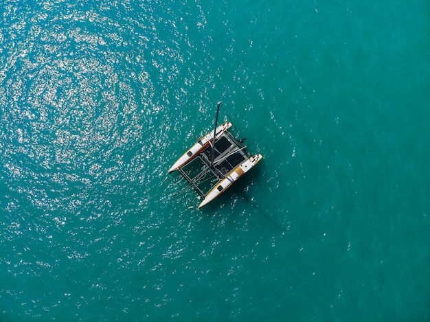 Vista aérea de la increíble laguna azul profundo en un caluroso día de verano con un catamarán de vela a través del mar. Vista superior.