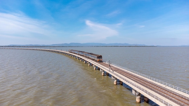 Vista aérea de un increíble tren de viaje estacionado en un puente ferroviario flotante sobre el agua del lago