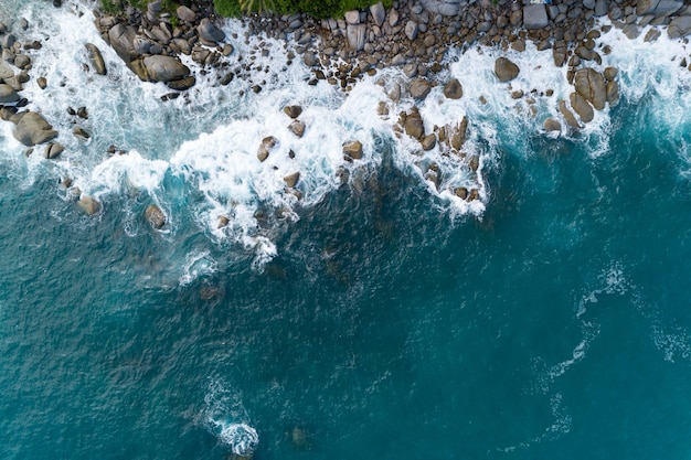 Vista aérea incrível de ondas quebrando em rochas vista da natureza e lindo mar tropical com vista da costa do mar na temporada de verão. Imagem de Drone Vista de alto ângulo