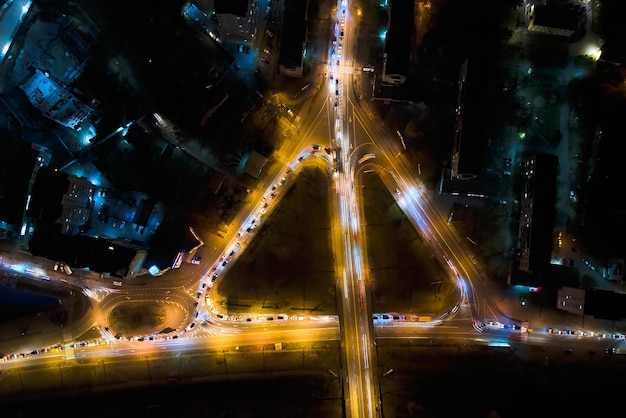 Vista aérea de la intersección de carreteras con tráfico pesado en movimiento rápido por la noche Vista superior del transporte urbano Hora punta con luces de sendero de coche de desenfoque de movimiento