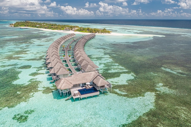 Vista aérea de la isla Maldivas, resort de lujosas villas acuáticas y muelle de madera. Hermoso cielo y océano