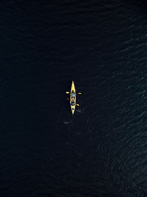 Vista aérea del kayak amarillo en el agua del lago azul oscuro