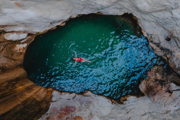 Vista aérea del lago de la cascada dimosari con una mujer feliz flotando en la espalda