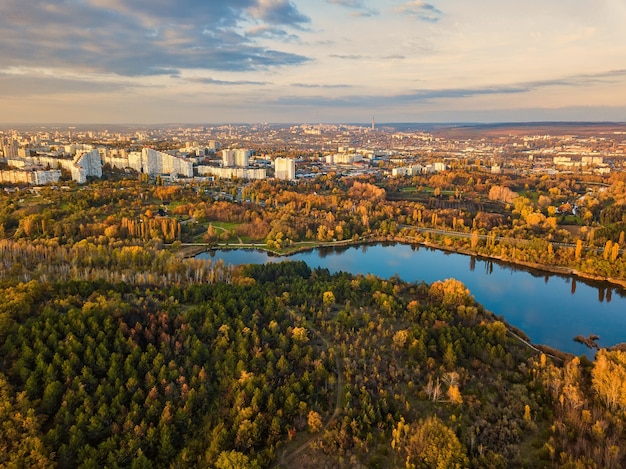 Vista aérea de un lago en un parque con árboles en otoño. Kishinev, Moldavia. Vuelo aéreo épico sobre el agua. Árboles coloridos del otoño durante el día.