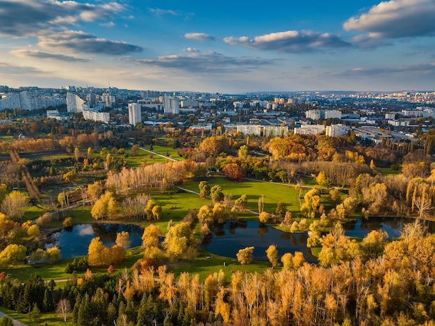 Vista aérea de un lago en un parque con árboles en otoño. Kishinev, Moldavia. Vuelo aéreo épico sobre el agua. Árboles coloridos del otoño durante el día.