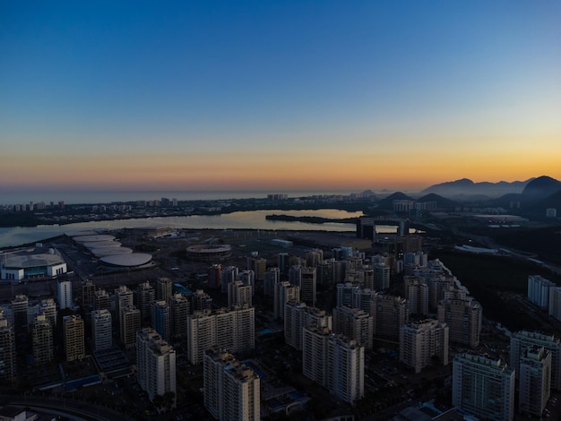 Vista aérea de la laguna de Jacarepaguá en Río de Janeiro Brasil Edificios residenciales y montañas alrededor del lago Playa de Barra da Tijuca en el fondo Día soleado Atardecer Drone foto