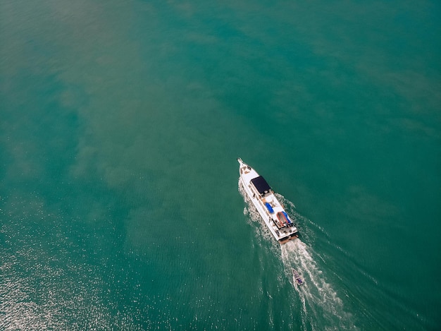 Vista aérea de la lancha rápida y un barco detrás de él navegando cerca de la costa de Tailandia, rastro blanco en el agua; concepto de buques.