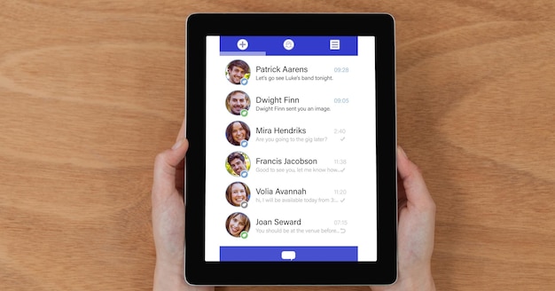 Foto vista aérea de la lista de chat en la computadora de la tableta sostenida por una persona en la mesa