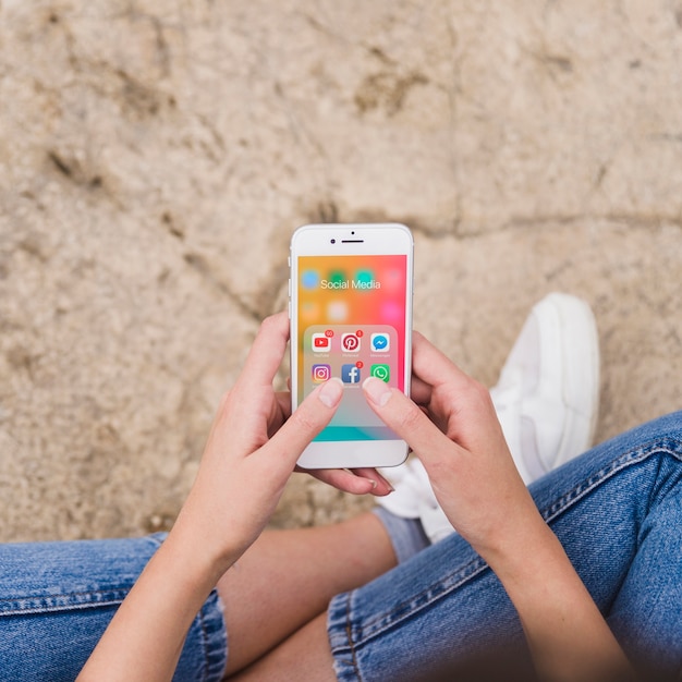 Vista aérea de la mano de la mujer mediante teléfono móvil con notificaciones en la pantalla