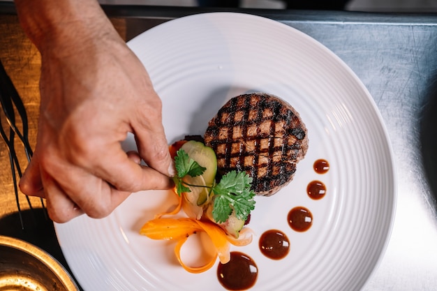 Vista aérea de la mano de un profesional adornar un plato ingenio reunirse